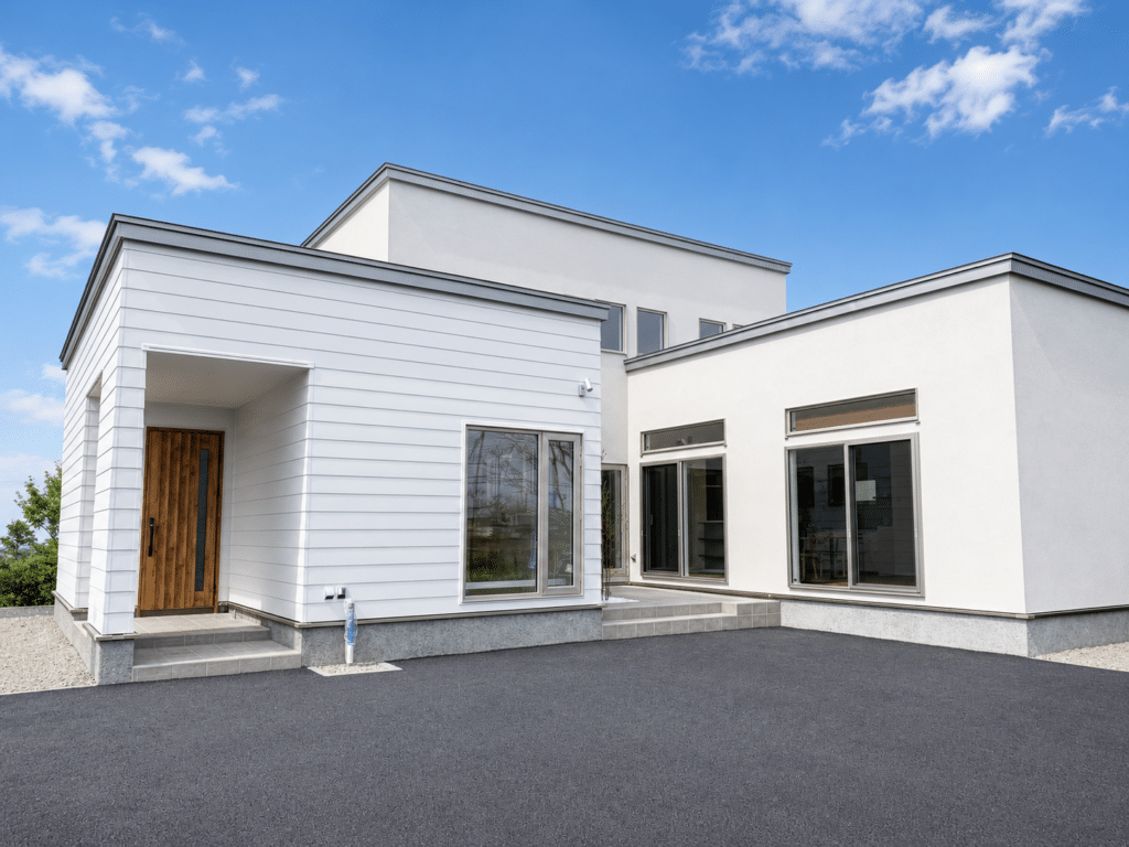 白い外壁と木製玄関ドアが印象的な新築住宅の外観