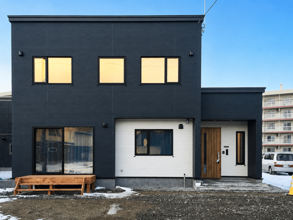 黒い外壁と木目の玄関ドアがある二階建て住宅の外観